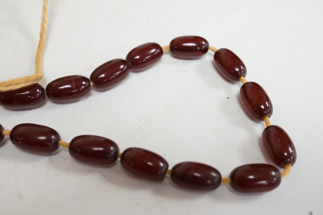 A single strand amber bead necklace, with filigree metal spacers, 48cm, gross 84 grams, together with a group of loose graduated simulated cherry amber beads, gross weight 117 grams.